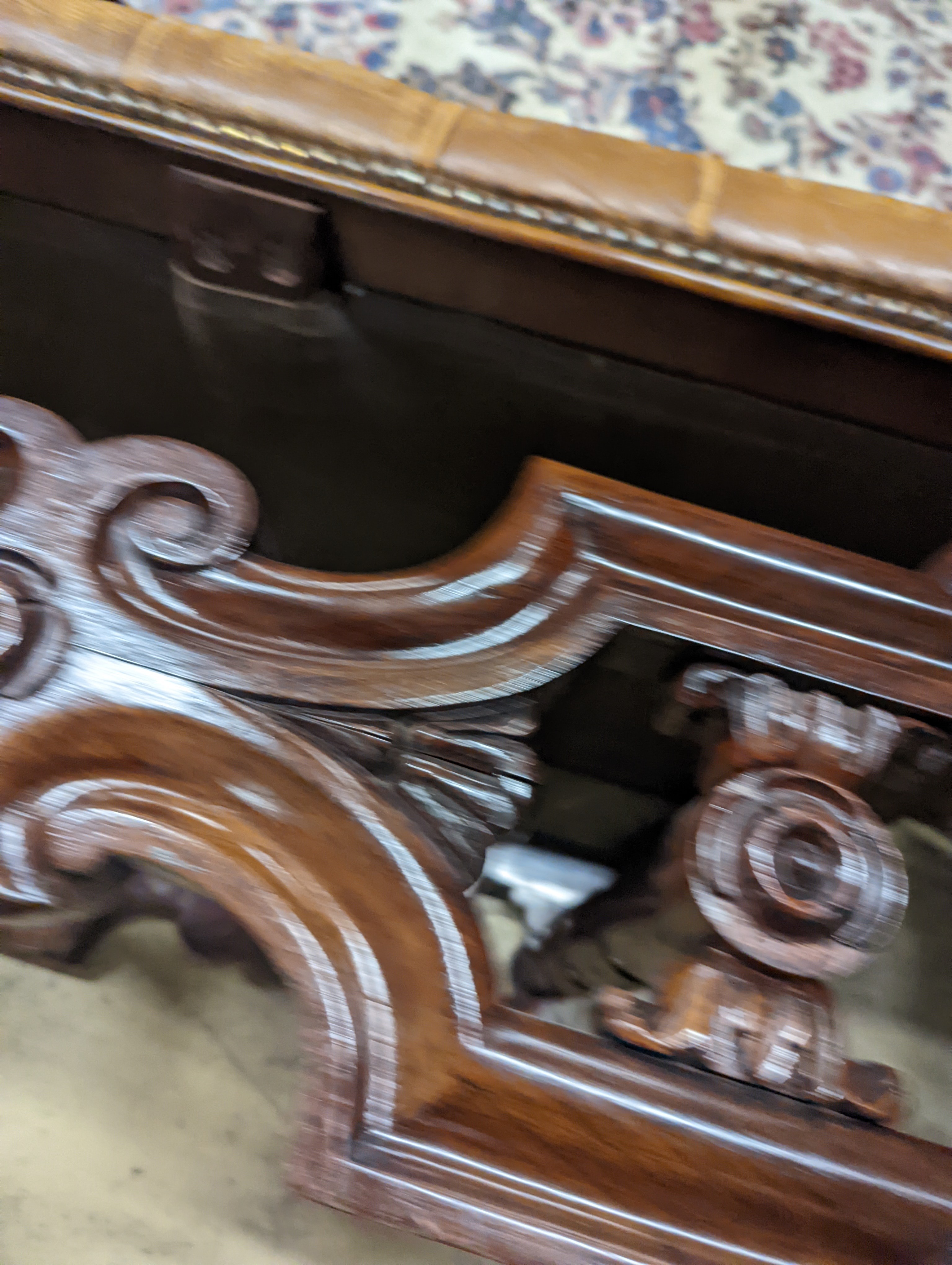 A Victorian carved X-framed rosewood footstool, upholstered in a buttoned brown leather, width 90cm depth 57cm height 42cm